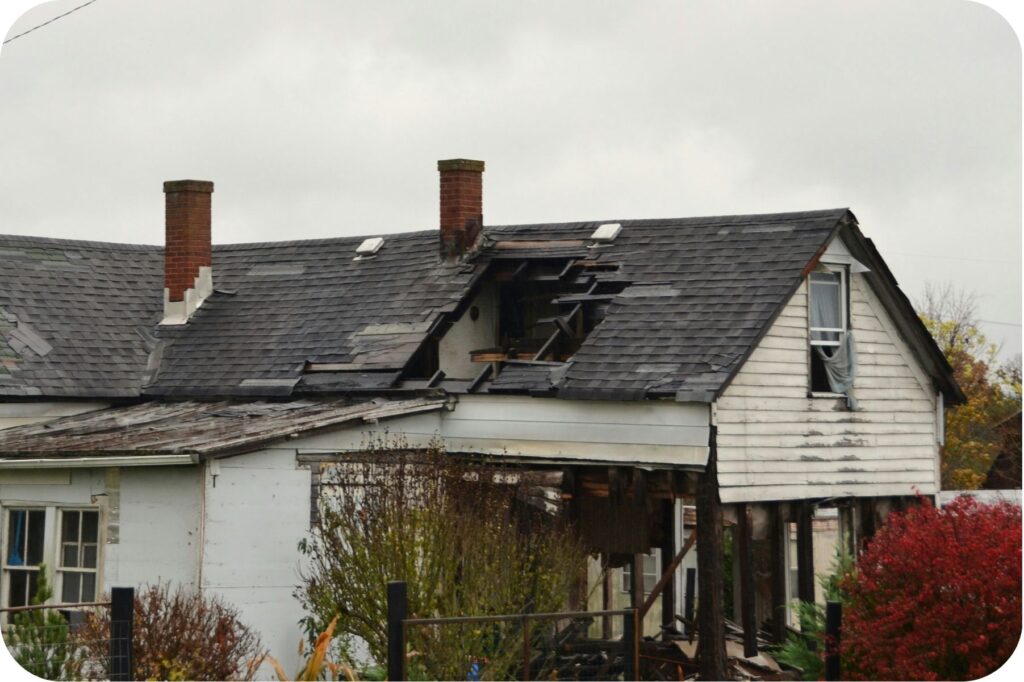 A damaged home with a collapsed roof, illustrating insurance displacement after fire or water loss.