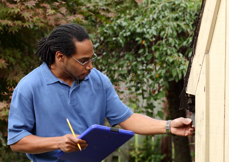 An insurance adjuster inspecting the exterior of a home with a clipboard to assess damage